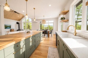 A modern kitchen with a wooden island, built-in cabinets, and pendant lighting.