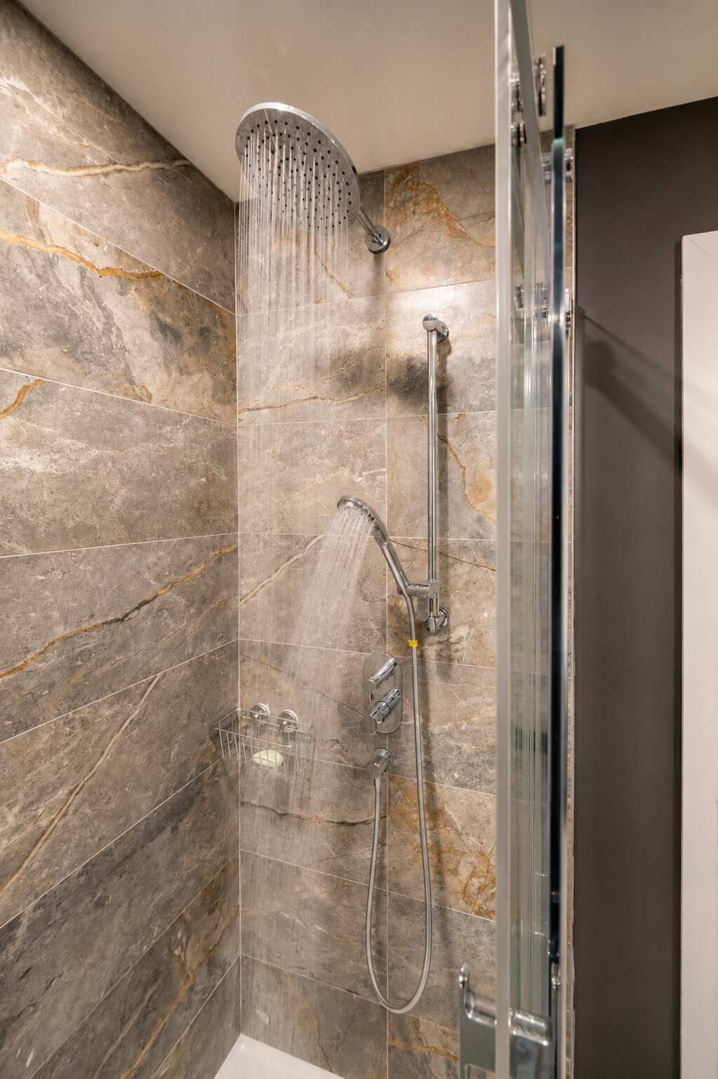 Une douche équipée d’un pommeau de douche à effet pluie, d’un pommeau de douche à main et d’un pommeau de douche à main doté d’une poignée.