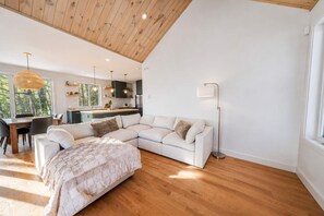Un espace de vie moderne comprenant un grand canapé en forme de L, un coin repas et une cuisine.