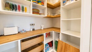 Une cuisine avec des armoires blanches, des plans de travail en bois et divers ustensiles de cuisine.