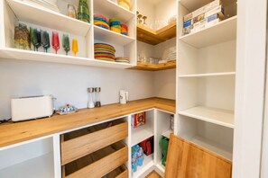A kitchen with white cabinets, wooden countertops, and various kitchenware.