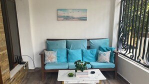 Un accogliente soggiorno con un divano color petrolio, un tavolino bianco e un quadro che raffigura una spiaggia.