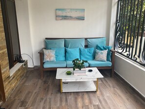 Un salon chaleureux avec un canapé turquoise, une table basse blanche et un tableau représentant une scène de plage.