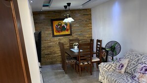 Un soggiorno con divano, un tavolo da pranzo con sedie, televisore e una ventola a parete.