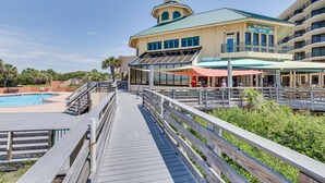 A resort with a pool, a bar/lounge area, and a building with a tower. - Luau II 6930 (Miramar Beach)