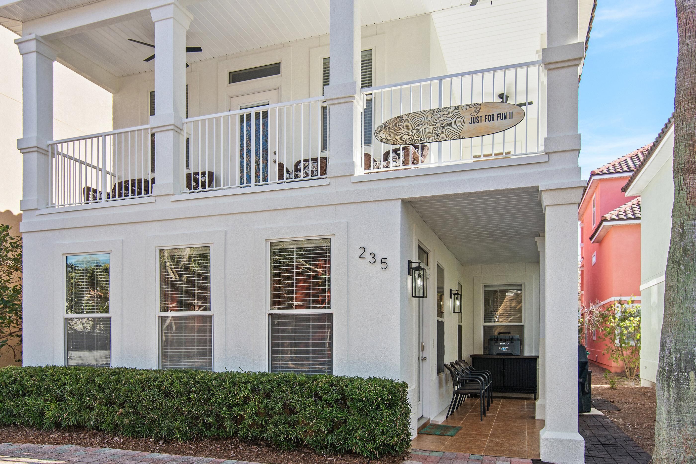 A two-story house with a balcony, number 235, and a small outdoor seating area.