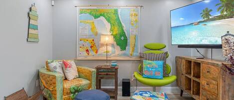 Ein Wohnzimmer mit einer großen Karte von Florida, einem Fernseher, der eine Strandansicht zeigt, und einer Holzkabine.