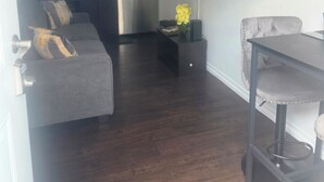 Eine moderne Küche mit Kühlschrank, Mikrowelle und Herd. Ein graues Sofa mit Zierkissen und ein kleiner Tisch mit einem Blumenstrauß.