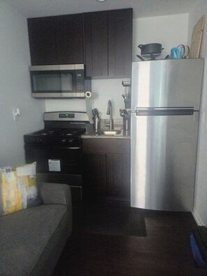 A compact kitchen with a stove, microwave, sink, and refrigerator. - Cozy Local Weekend Escape (Whittier)
