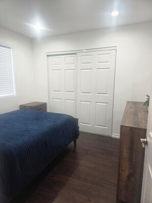 Ein Schlafzimmer mit einem Bett, einem Kleiderschrank, einem Nachttisch und einer Holzkommode.