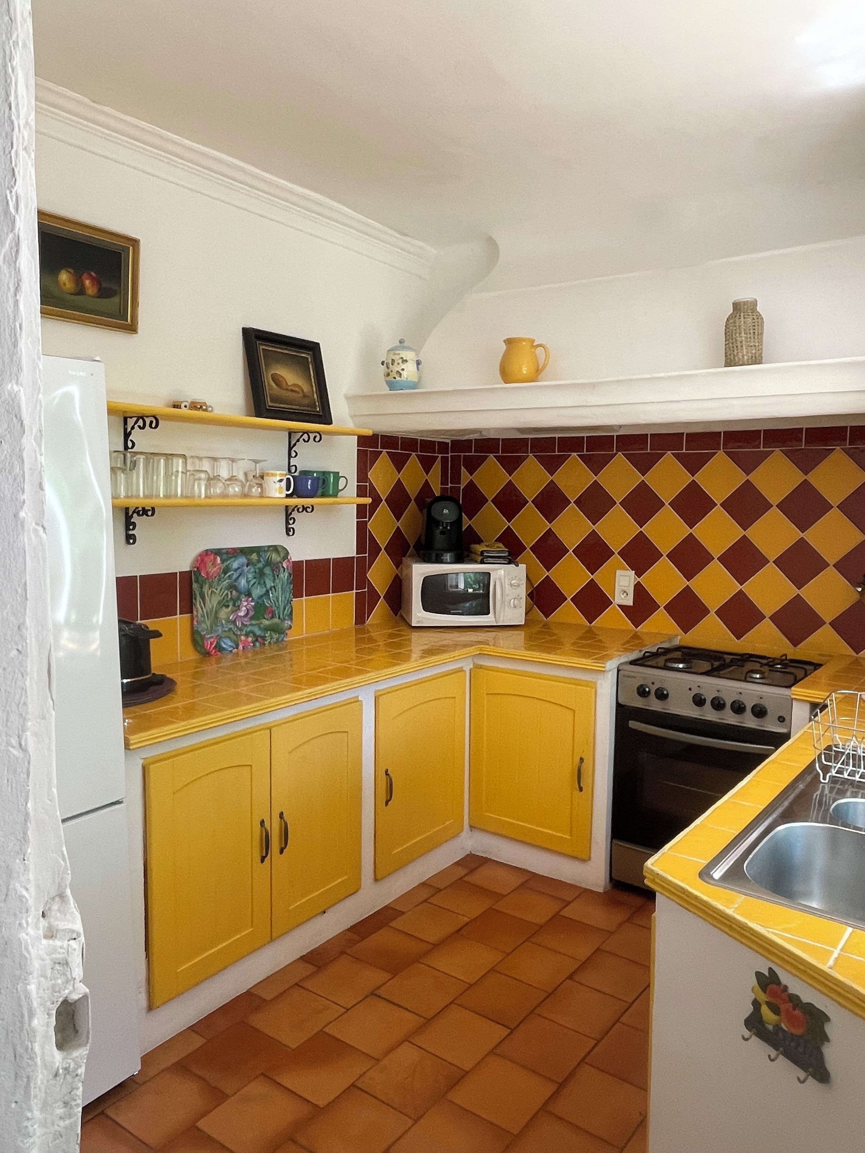 Une cuisine avec des meubles de couleur jaune, un four à micro-ondes, une cuisinière et un évier.