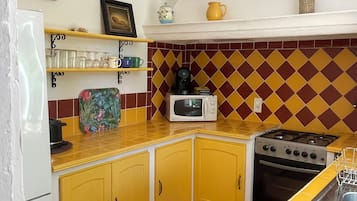 Une cuisine avec des meubles de couleur jaune, un four à micro-ondes, une cuisinière et un évier.