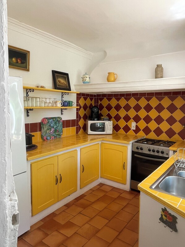 A kitchen with yellow cabinets, a microwave, a stove, and a sink.