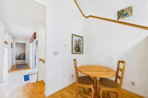 A dining area with a round wooden table and two chairs, a staircase with a wooden handrail, and a framed picture on the wall.