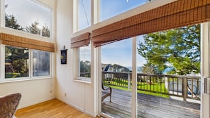 Una habitación con ventanas amplias, una terraza de madera y vistas a un paisaje verde.