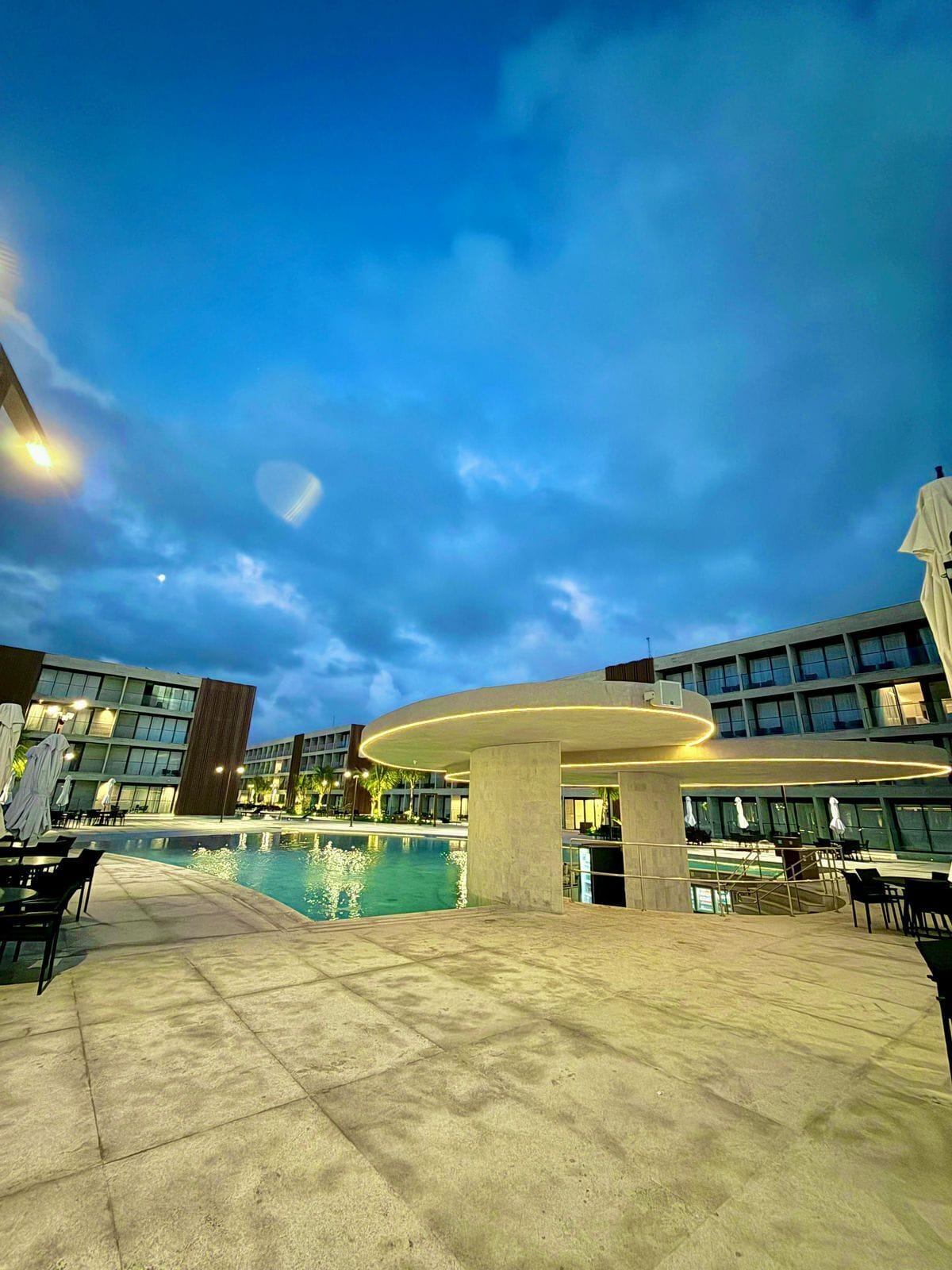 A modern hotel pool area with a circular seating area and a large pool.