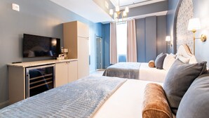A hotel room with a bed, a desk with a TV, a wardrobe, and a bathroom door. - Hollyhock Suite 406: 1 bed/1 bath (Louisville)