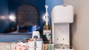 A coffee station with a Monin bottle, a coffee machine, and various coffee pods. - Hollyhock Suite 406: 1 bed/1 bath (Louisville)