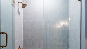 A modern bathroom with a white bathtub, a toilet, and a shower with a glass enclosure. - Hollyhock Suite 406: 1 bed/1 bath (Louisville)