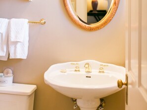 A bathroom with a white sink, gold faucets, a round mirror, and a towel rack with white towels. - Deluxe Room 7-Double room-Private Bathroom-Standard (Fish Creek)