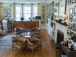 A spacious living room with a piano, leather chairs, a fireplace, and a wall adorned with framed pictures. - Deluxe Room 7-Double room-Private Bathroom-Standard (Fish Creek)
