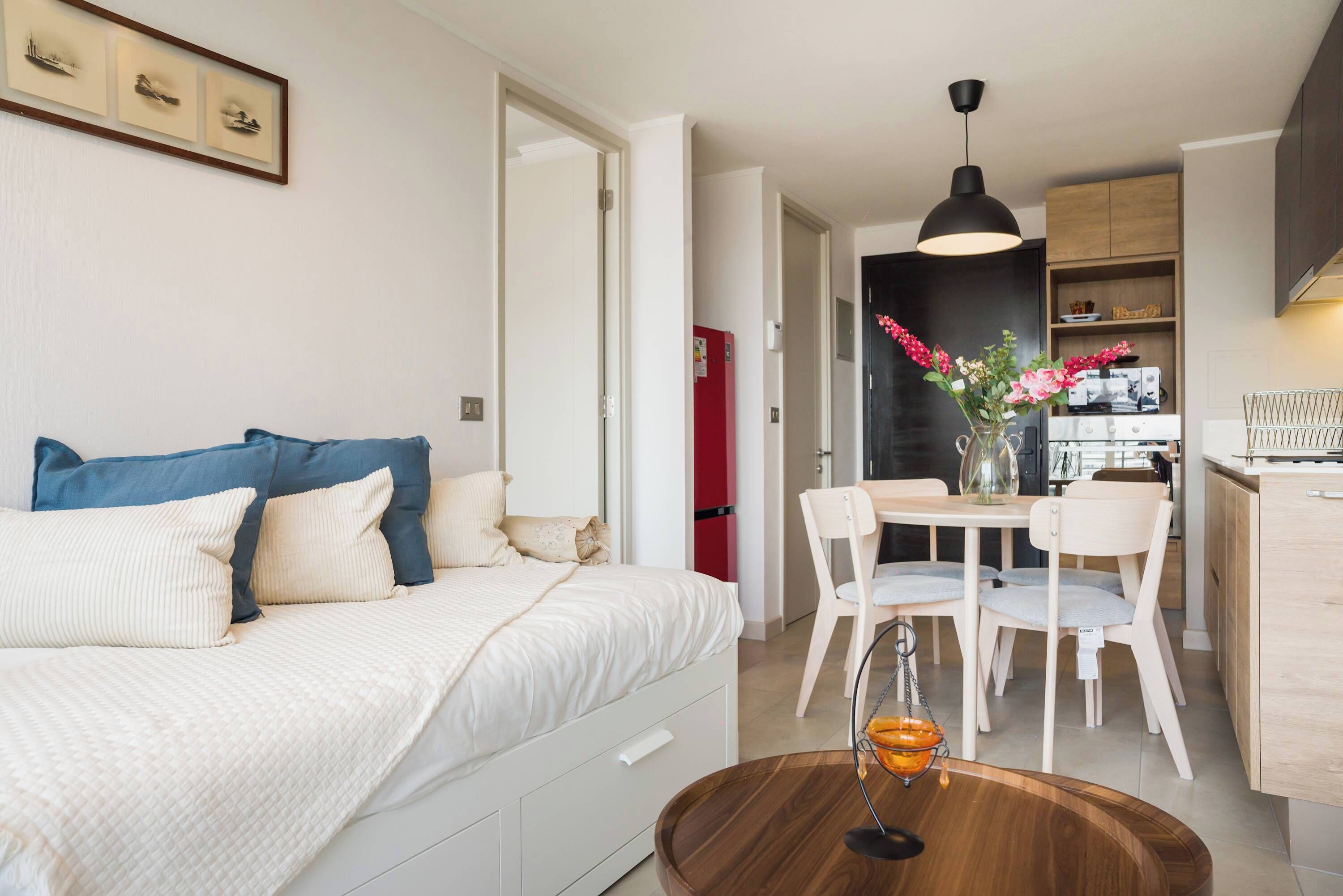Un apartamento moderno con cama, una mesa de comedor con sillas, una zona de cocina y un espacio de sala.
