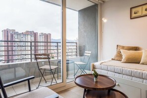 A balcony with a sofa, a chair, and a table. - Beautiful Apartment in Nunoa with Balcony and Pool (Ñuñoa)