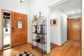 A wooden door, a metal shelf with decorative items, a small framed picture, and a wooden floor. - Sunriver's Klamath Lane - Hot Tub & SHARC Passes (Sunriver)