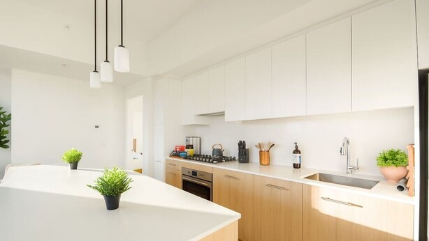 Una cucina moderna con mobili bianchi, un'isola centrale e un forno integrato.