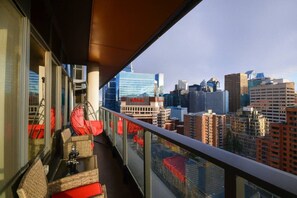 Ein Balkon mit Korbmöbeln und Blick auf die Stadt.
