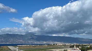 Vista de una zona costera con una pista de aterrizaje, edificios y montañas al fondo.