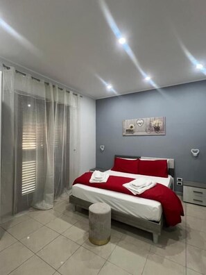 A modern bedroom with a bed, curtains, a wall-mounted artwork, and a bedside table. - Incanto B&B (Reggio Calabria)