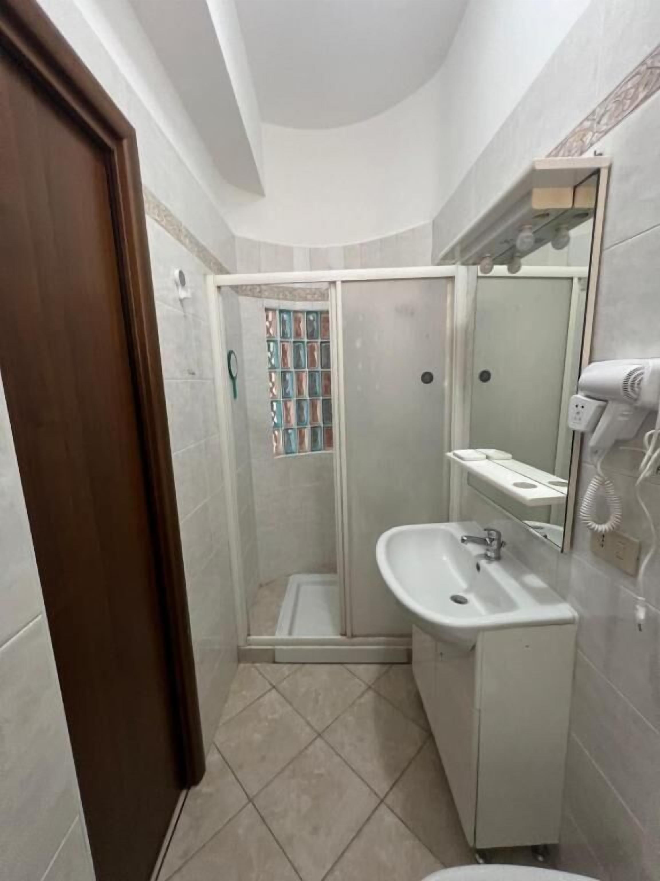 Un baño pequeño con ducha, lavabo y espejo.