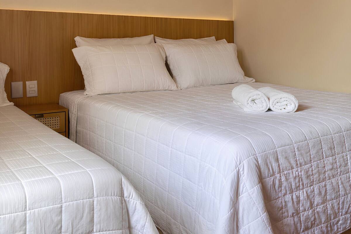 A hotel room with two beds, a wooden ceiling, and a simple, clean design.