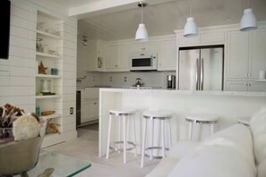 A modern kitchen with white cabinetry, a central island with stools, and pendant lighting.