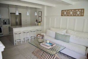 A modern kitchen with white cabinetry, stainless steel appliances, and a central island with stools.