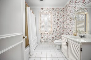 A bathroom with a toilet, a sink with a mirror, and a shower curtain. - Le Hudson Hideaway | Large Mid Century Bungalow with Ultimate Privacy on 1 Acre (Hudson)