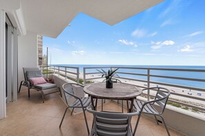 A balcony with a view of the beach, a table with chairs, and a potted plant. - 7th-Floor Beachfront Marco Island Condo with Panoramic Ocean & Sunset Views (Marco Island)