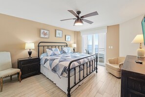 A bedroom with a bed, bedside tables, a chair, a desk, a ceiling fan, and a view of the outdoors. - 7th-Floor Beachfront Marco Island Condo with Panoramic Ocean & Sunset Views (Marco Island)