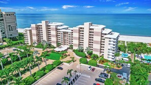 A high-rise hotel with multiple balconies, a parking lot, and a pool area. - 7th-Floor Beachfront Marco Island Condo with Panoramic Ocean & Sunset Views (Marco Island)