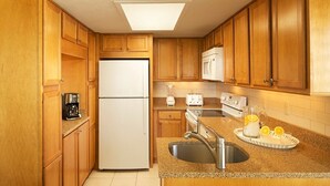 Eine Küche mit Holzausstattung, einem Kühlschrank, einer Mikrowelle, einem Toaster, einer Spüle und einer Kaffeemaschine.