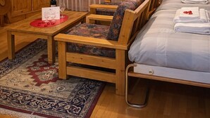 Ein mit Holzmöbeln eingerichteter Raum mit einem Bett, einer Couch, einem Fernseher und einem Tisch mit einer Flasche und Gläsern.