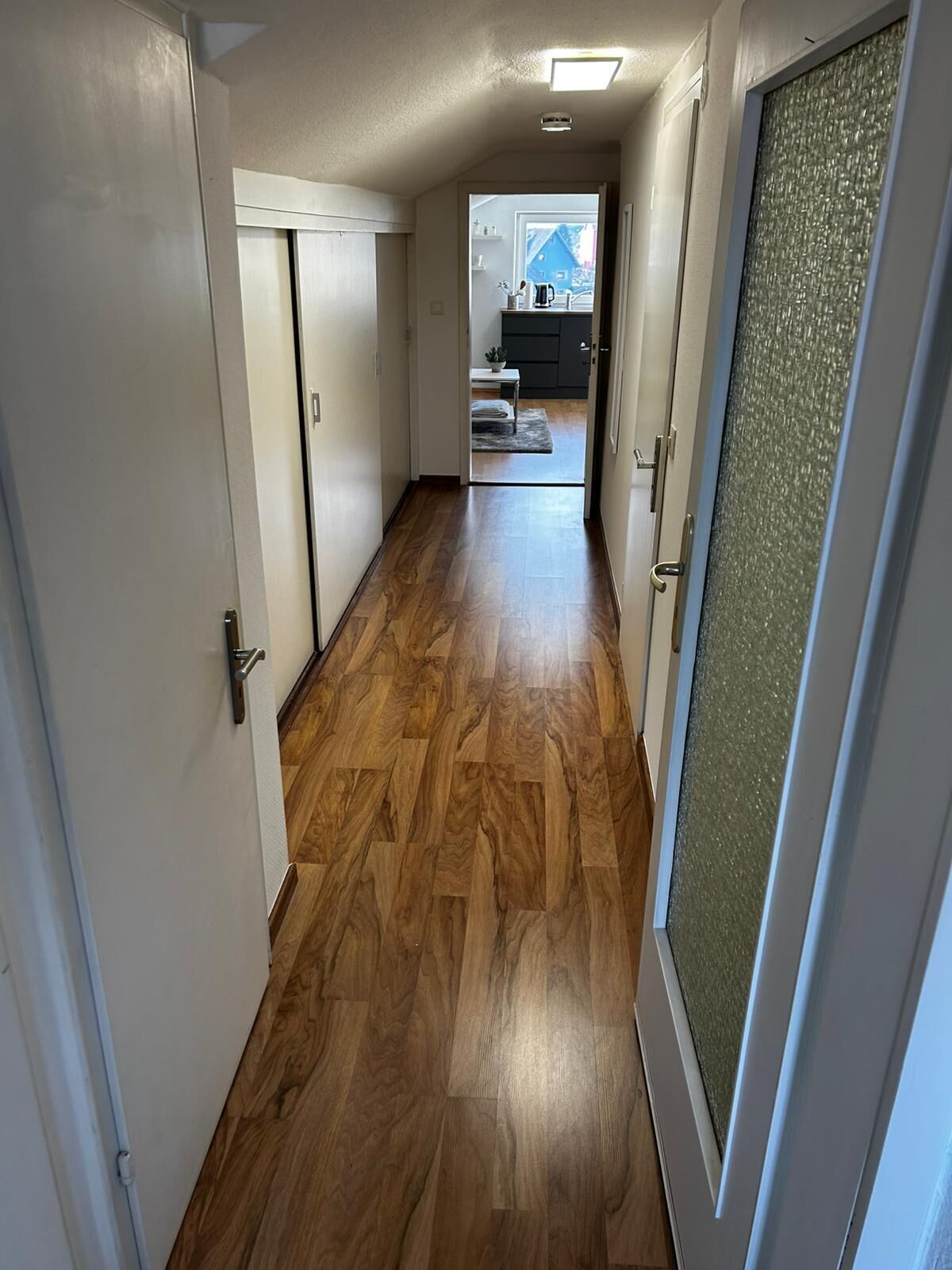 Un pasillo con piso de madera que conduce a una cocina.