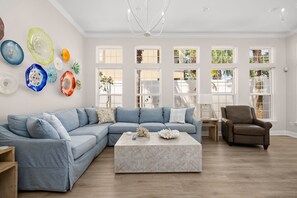 A modern living room with a sectional sofa, a coffee table, and a brown armchair. - Beach House · Private Beach · Private Pool & Backyard · Steps to Sand (Miramar Beach)