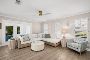A modern living room with a sectional sofa, a round coffee table, and a patterned armchair. - Beach House · Private Beach · Private Pool & Backyard · Steps to Sand (Miramar Beach)