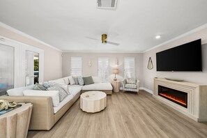 Ein modernes Wohnzimmer mit einer Eckcouch, einem runden Couchtisch, einem Kamin und einem an der Wand befestigten Flachbildfernseher.