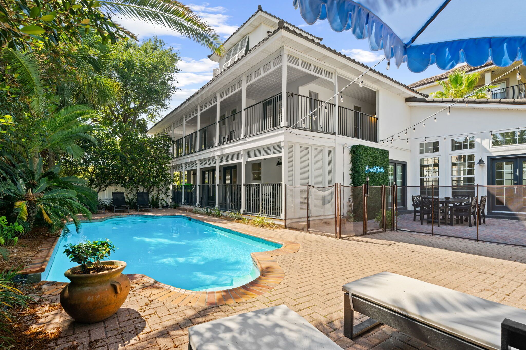 A two-story building with a swimming pool, outdoor seating, and a covered patio area.