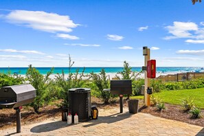 Un espace barbecue équipé d’un gril, de poubelles et d’un extincteur.
