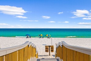 A wooden boardwalk leading to a beach with clear turquoise water and a few people under umbrellas. - Beach House · Private Beach · Private Pool & Backyard · Steps to Sand (Miramar Beach)