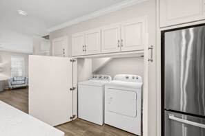 A compact kitchen with white cabinetry, a stainless steel refrigerator, a double oven, and a washing machine. - Beach House · Private Beach · Private Pool & Backyard · Steps to Sand (Miramar Beach)